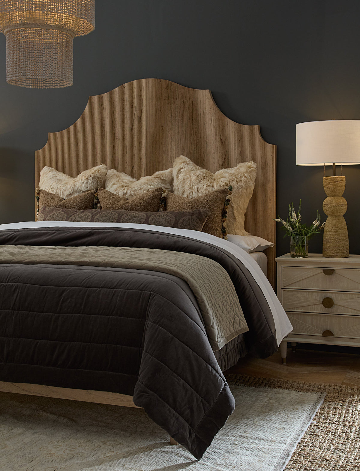 Gabby cane headboard bed in a moody Lake and Mountain bedroom setting at Gabriella White, styled with layered earth-tone bedding, a rattan pendant light, and warm wood nightstand in an eclectic transitional interior.