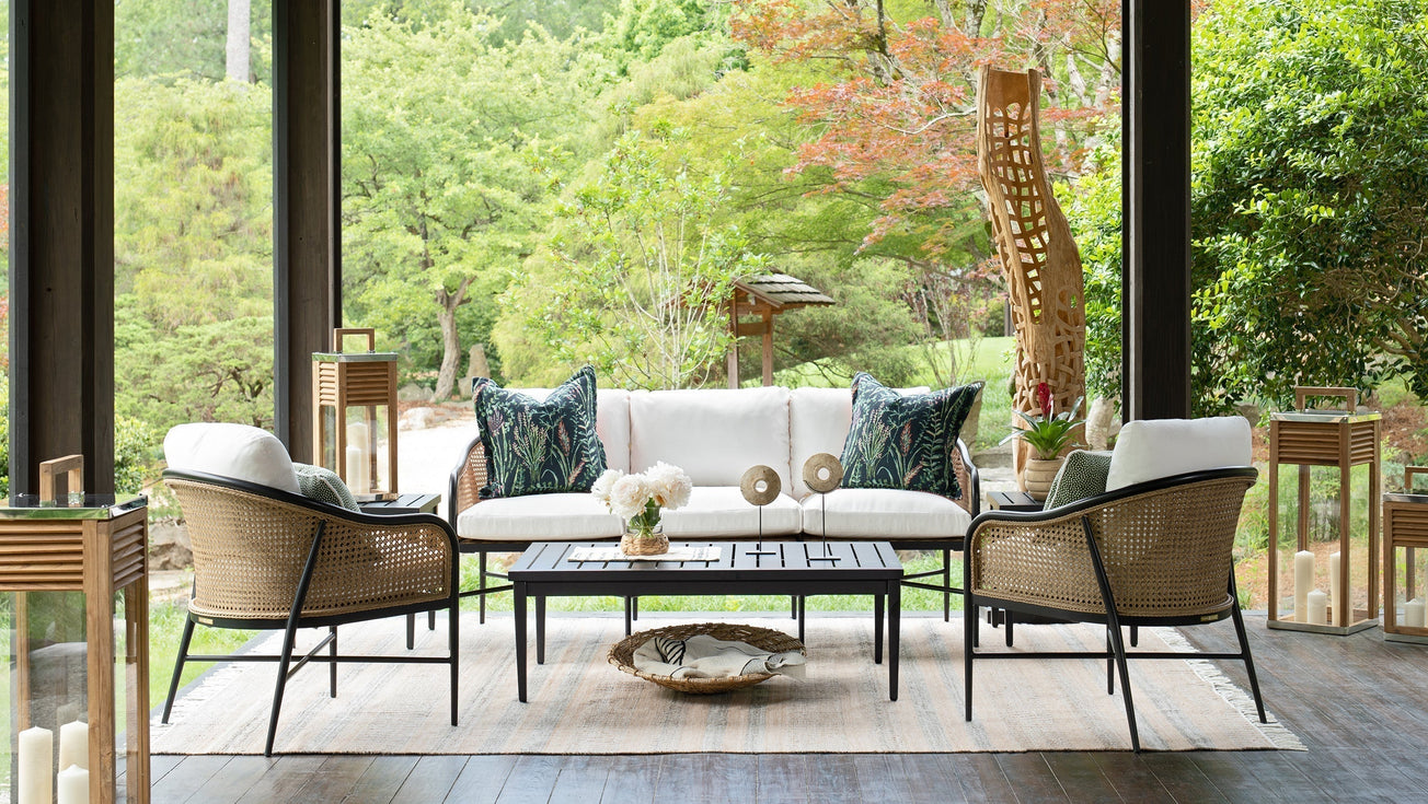 Summer Classics Havana Black woven lounge chairs and Brookings outdoor sofa with white cushions and Enchanted botanical pillows styled on a covered porch with lush garden views
