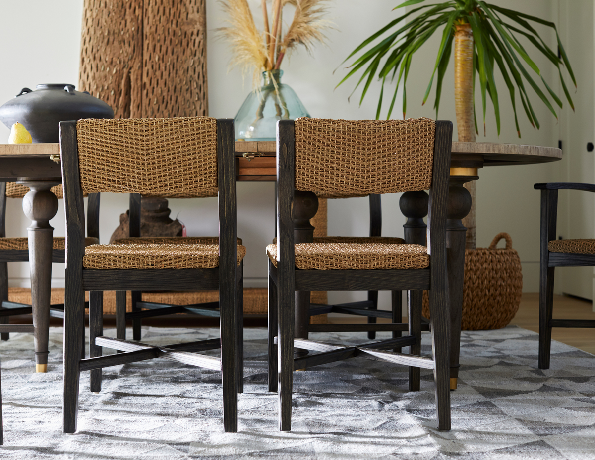 Gabby rattan and ebonized wood dining chairs styled in an eclectic transitional dining room at Gabriella White, featuring natural woven textures, a dark wood dining table, and layered organic accessories.